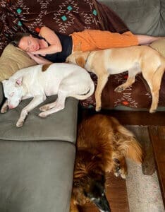 3 stray dogs, Maeve and Gertie and Margot napping with adopter Yasya