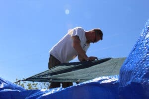 Team member, Ari attaching shade cloth to kennel roof, Lava Fire