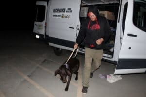 Team member, Ari unloading a RRAAP dog and walking back to facility